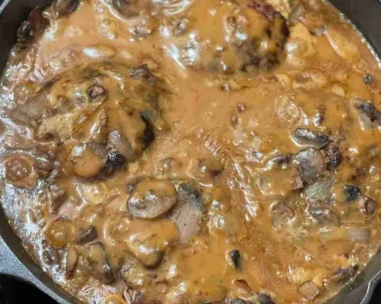 Hamburger steak smothered in brown gravy with mushrooms and onions